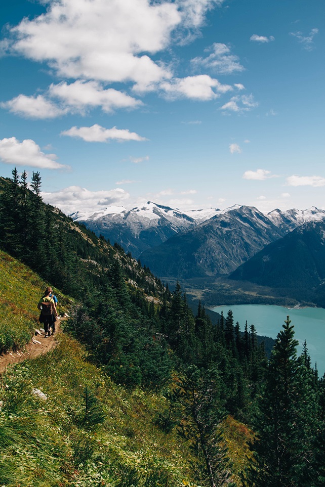 People hiking up side of mountain with lake