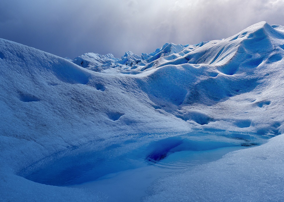 Small clear pool in snow covered mountains