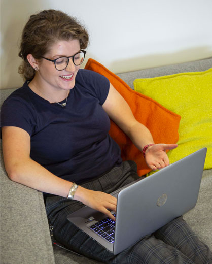 woman conversating on computer while relaxing on couch