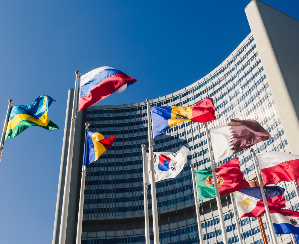 Daytime photo of United Nations building in Vienna, Austria with flags of nations and bright blue sky